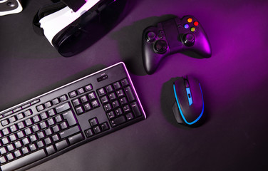 Top view a gaming gear, mouse, keyboard, joystick, headset, VR Headset on black table background.