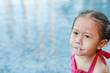 Mucus flowing from nose of little asian child girl while swimming at pool.