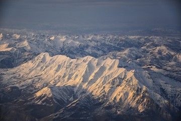 Wall Mural - Aerial view from airplane of the Wasatch Front Rocky Mountain Range with snow capped peaks in winter including urban cities of Provo, Farmington Bountiful, Orem and Salt Lake City. Utah. United States