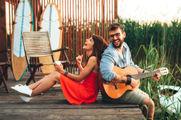 Wall Mural - Man and woman singing and playing guitar by the river