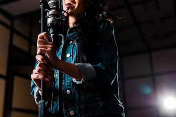 Wall Mural - partial view of woman singing near microphone in recording studio