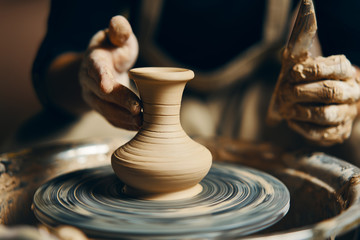 Potter modeling ceramic pot from clay on a potter's wheel