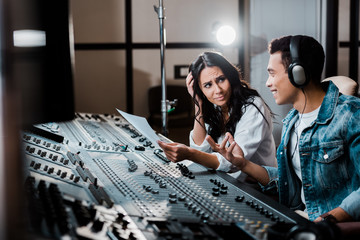 Wall Mural - two sound producers talking while working at mixing console in recording studio