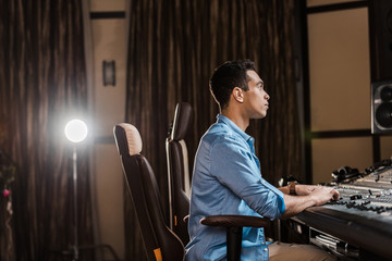 Canvas Print - concentrated sound producer sitting in office chair and working at mixing console