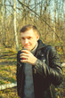 © Anton Dios - Man drinking coffee in cold woods Casual man in outwear enjoying hot drink in paper cup standing in sunny seasonal forest