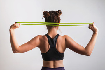 Young athletic woman doing exercises with fitness rubber band