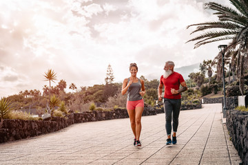 Happy sporty couple running outdoor - Fit friends jogging and training together  outside - People, health, fitness and sport lifestyle concept