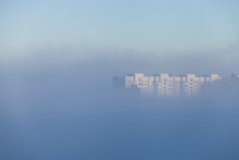 A Lonely Tall Building Peeking Out From Under A Dense Layer Of Fog That Covered The City In The Early Morning. City Concept. City In The Clouds.