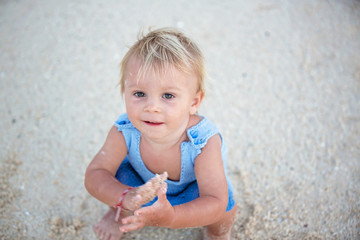 Sticker - Cute toddler baby boy playing with sand on tropical beach, cute shot from above, baby smiling, wearing knitted onesie