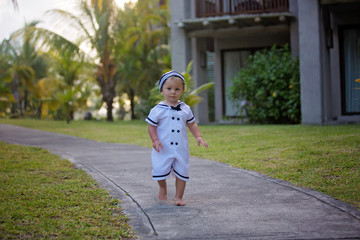 Sticker - Beautiful toddler boy, dressed as a sailor, playing on the beach on sunset, enjoying tropical magical holiday vacation