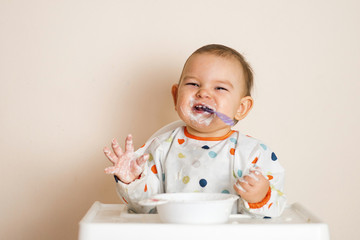 A Little baby eating her dinner and making a mess