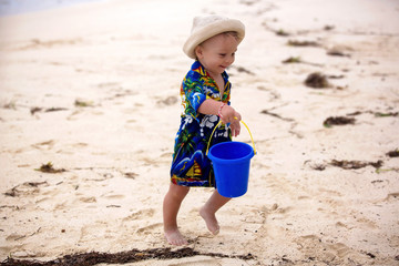 Wall Mural - Cute toddler baby boy playing with beach toys on tropical beach