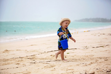 Wall Mural - Cute toddler baby boy playing with beach toys on tropical beach