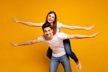 Portrait of his he her she two nice attractive cheerful cheery funny optimistic people having fun trip fly vacation holiday travel isolated over vivid shine bright yellow background