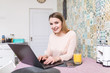 © F8  \ Suport Ukraine - Smiling young woman using laptop in the kitchen at home