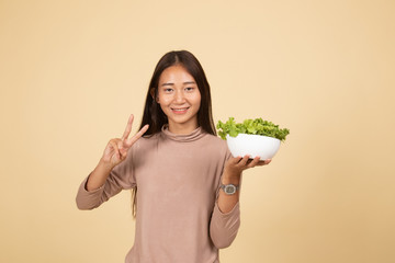 Healthy Asian woman show victory sign with salad.