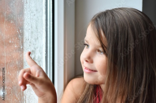Beautiful Happy Toddler Girl Looking Through The Window With