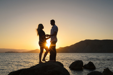 Loving couple enjoying sunset by the sea