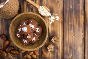 Wall Mural - Energy balls with coconut chips,almond,oats cereals and dates in the brown bowl on the wooden background.Top view.Copy space.