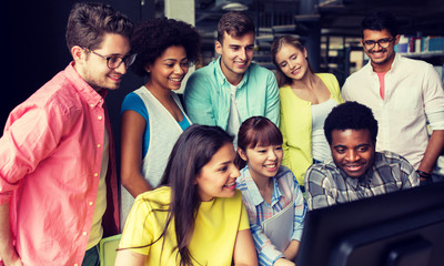 Poster - people, education, technology and school concept - group of happy smiling international students with computers at library in university