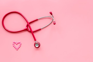 diagnostic and cure of cardiac disease with stethoscope and heart on pink background top view mock-up