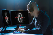Cybercrime, Hacking And Technology Concept - Male Hacker In Headset With Access Denied Messages On Computer's Screens Wiretapping Or Using Computer Virus Program For Cyber Attack In Dark Room