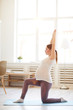 © Seventyfour - Side view full length portrait of pregnant woman doing yoga exercises at home, copy space