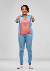 Wall Mural - gesture and people concept - smiling young african american woman showing thumbs up over grey background