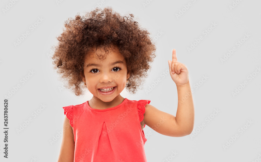 idea, warning and childhood concept - happy little african american girl pointing finger up over grey background - obrazy, fototapety, plakaty 