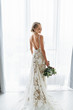 Awesome bride in a long wedding dress with a beautiful bouquet in hand and with charming smile
