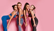 © Dmitry Lobanov - Group of four sport girls international friends posing on pink background. Sporty young woman in blue gray brown