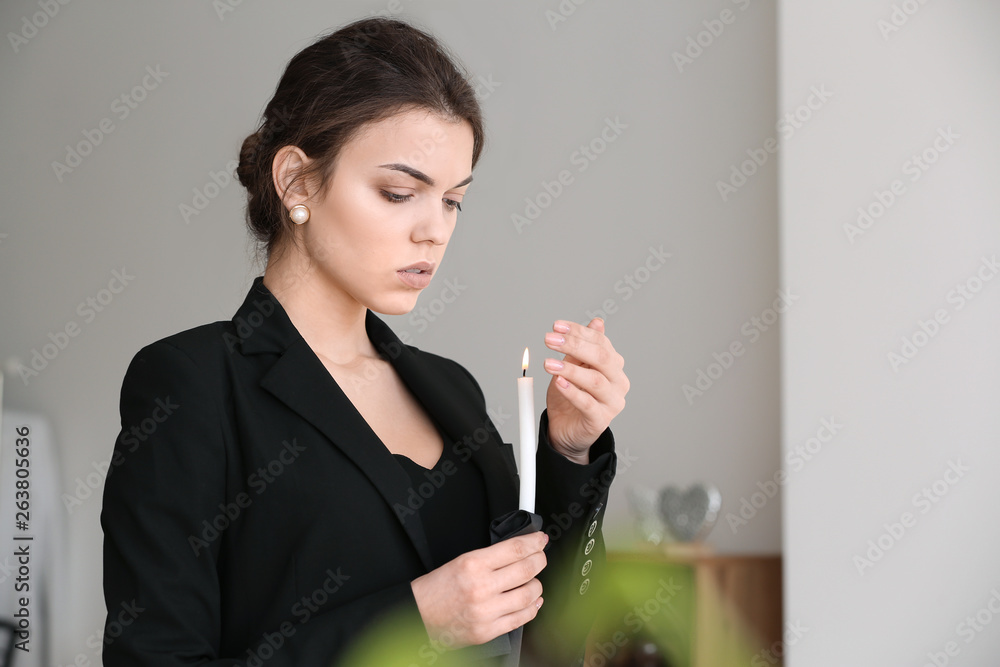 Woman with candle pining after her relative at funeral