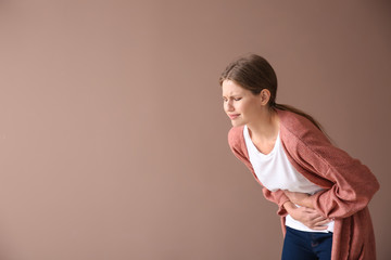 Sticker - Young woman suffering from pain on color background