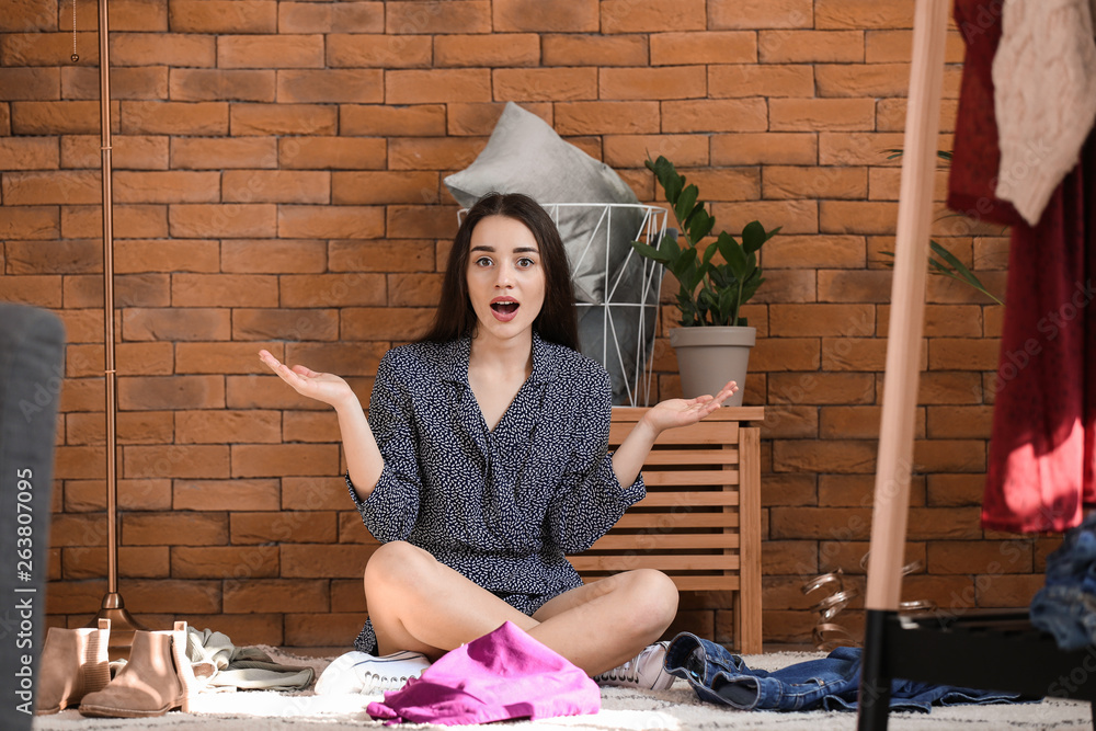 Shocked young woman choosing clothes in dressing room