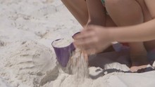 A Cute Girl On The Beach Plays In The Sand With A Mold For A Sandcastle