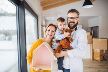 Wall Mural - A portrait of young family with a toddler girl moving in new home.