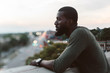 © Chelsea Victoria/Stocksy - A young man posing on a roof overlooking the city at sunset