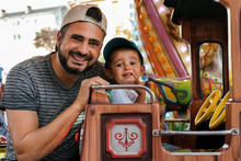 Father And Kid Having Fun In The Carousel