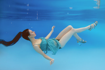 Wall Mural - surreal, concept, art portrait of beautiful gorgeous brunette young woman with make up underwater in the swimming pool on blue background 