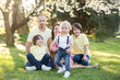© Tomsickova - Beautiful family, mother, father and three kids, boys, having familly outdoors portrait taken on a sunny spring evening, beautiful blooming garden, sunset time