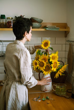 Girl Collects A Bouquet Of Sunflowers In The Kitchen