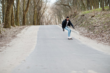 Wall Mural - Street style arab man in eyeglasses with longboard longboarding down the road.