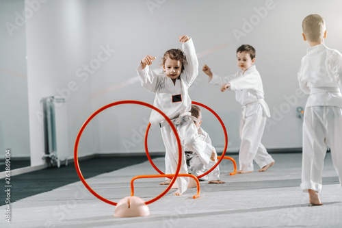 Small group of Caucasian kids in doboks practicing taekwondo and warming up for treining while standing barefoot Fototapete