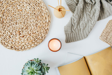 Boho style modern minimal home workspace desk with notebook, succulent, knitted plaid, candle, aroma sticks, straw wicker napkins on white background. Flat lay, top view lifestyle blog concept.