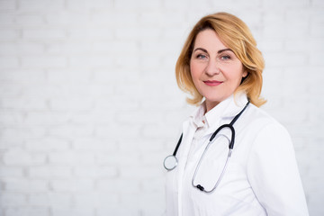 Wall Mural - mature female doctor posing over white wall with copy space