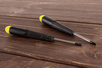 Wall Mural - Group of two whole screwdrivers with a yellow black plastic handle work item on brown wood