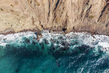 Wall Mural - Aerial tp view of sea waves with foam and Crimean yellow rocky coast, summer nature travel background