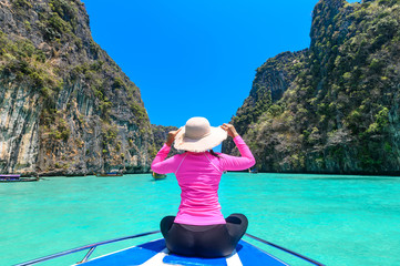 Young woman sitting at the front of boat in Maya Bay on Phi Phi Leh Island, Krabi Province, Thailand.