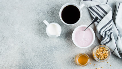 Wall Mural - Healthy Breakfast Concept. Strawberry or raspberry yogurt, granola, honey and cup of coffee on light concrete table background. View from above with copy space. Flat lay