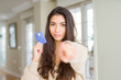 © Krakenimages.com - Young woman holding credit card as payment pointing with finger to the camera and to you, hand sign, positive and confident gesture from the front